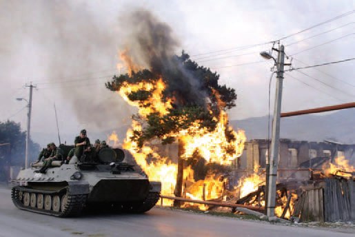 Российский МТ-ЛБВ проходит мимо горящего здания, ЮжнаяОсетия, август 2008 года